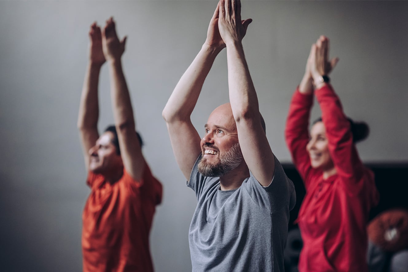 Kolme henkilöä kädet ojennettuna pään yläpuolella.